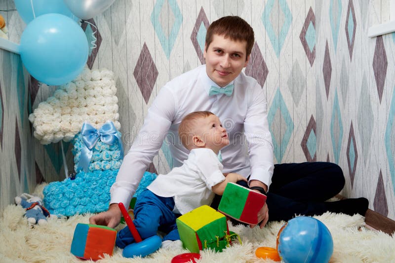 Small cute male child with father on the floor with toys during a photo shoot in the room in 1 year. Small cute male child with father on the floor with toys during a photo shoot in the room in 1 year