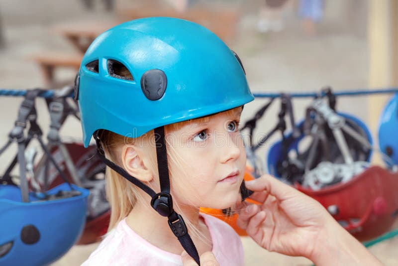 Liten gullig blond flicka som sätter på hjälm Avla portiondottern till den pålagda hjälmen för extrem sportrekreation Föräldern t arkivfoton Liten gullig blond flicka som sätter på hjälm Avla portiondottern till den pålagda hjälmen för extrem sportrekreation Föräldern t arkivfoton