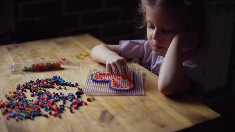 Liten gullig flicka som spelar med den f?rgrika mosaiken