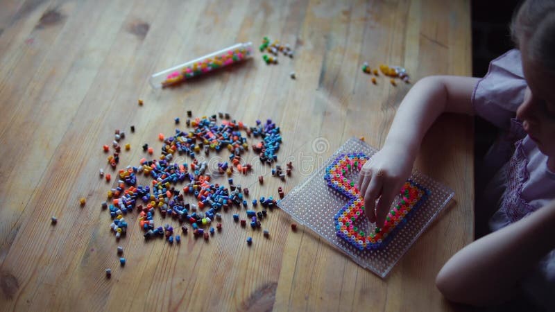 Liten gullig flicka som spelar med den f?rgrika mosaiken