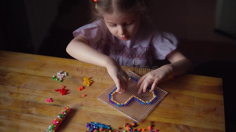 Liten gullig flicka som spelar med den f?rgrika mosaiken