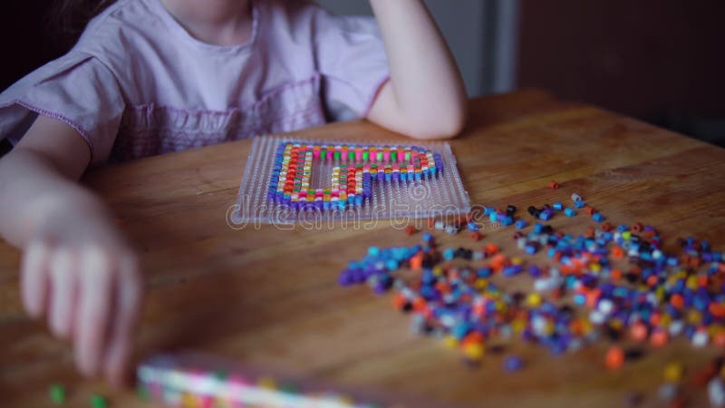 Liten gullig flicka som spelar med den f?rgrika mosaiken