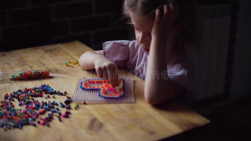 Liten gullig flicka som spelar med den färgrika mosaiken