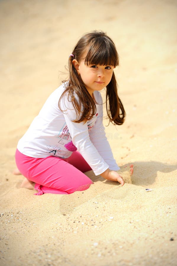 Liten gullig flicka som spelar på sand på stranden royaltyfria foton