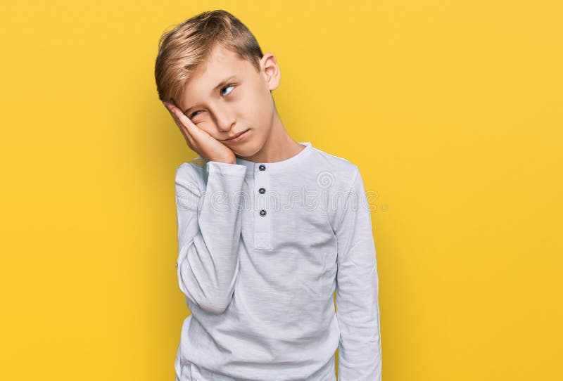 Liten kaukasisk pojke som bar sig vardagskläder som ser trött ut och uttråkad med depressionsproblem med överskjutna vapen arkivfoto