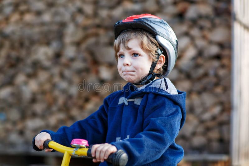 Liten pojke som cyklar i byn eller staden. Glad förskolebarn på baljcykel med kul. Fritid utomhus och royaltyfri foto