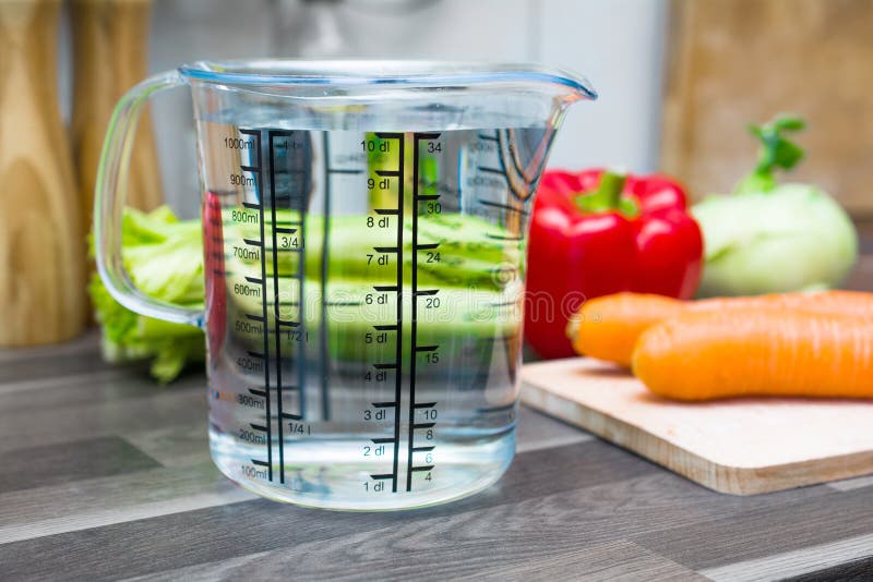 1 Liter / 1000ml / 10dl Of Water In A Measuring Cup On A Kitchen Counter With Vegetables