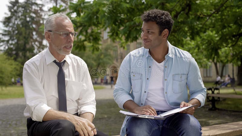 Literature teacher giving advice to Hispanic student about essay writing stock image Literature teacher giving advice to Hispanic student about essay writing stock image