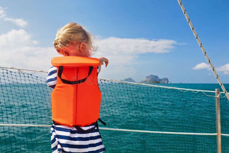Litet barn i flytväst ombord av segelbåten