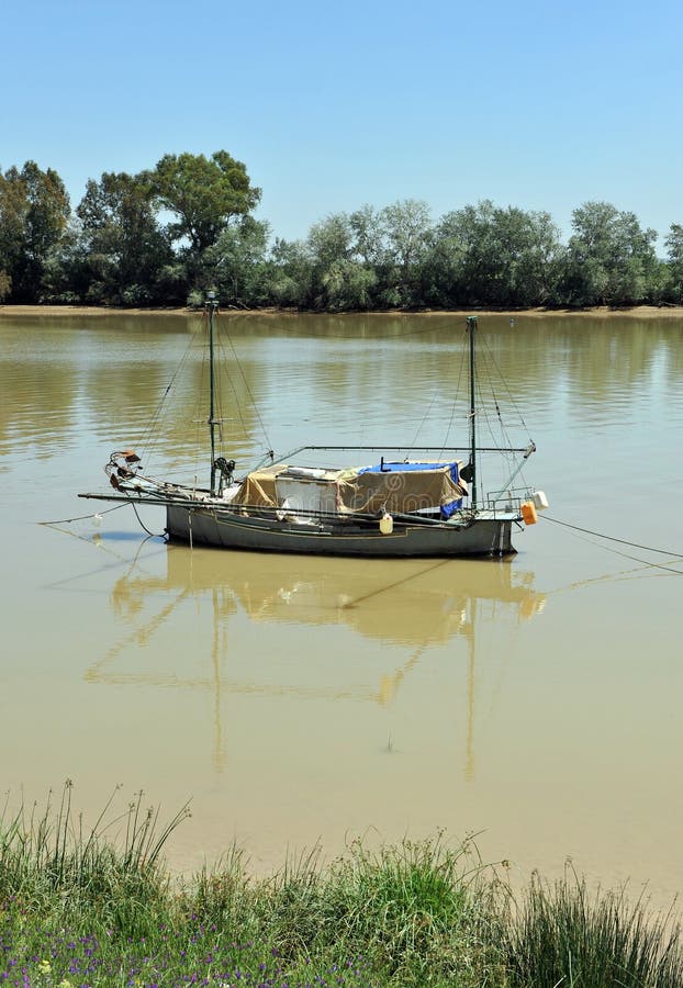 Litet fartyg på den Guadalquivir floden, som den passerar till och med Coria del Rio de Janeiro, det Seville landskapet, Andalusi royaltyfria bilder Litet fartyg på den Guadalquivir floden, som den passerar till och med Coria del Rio de Janeiro, det Seville landskapet, Andalusi royaltyfria bilder