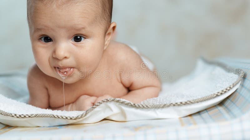 Little beautiful baby drools lying on his stomach. Little beautiful baby drools lying on his stomach