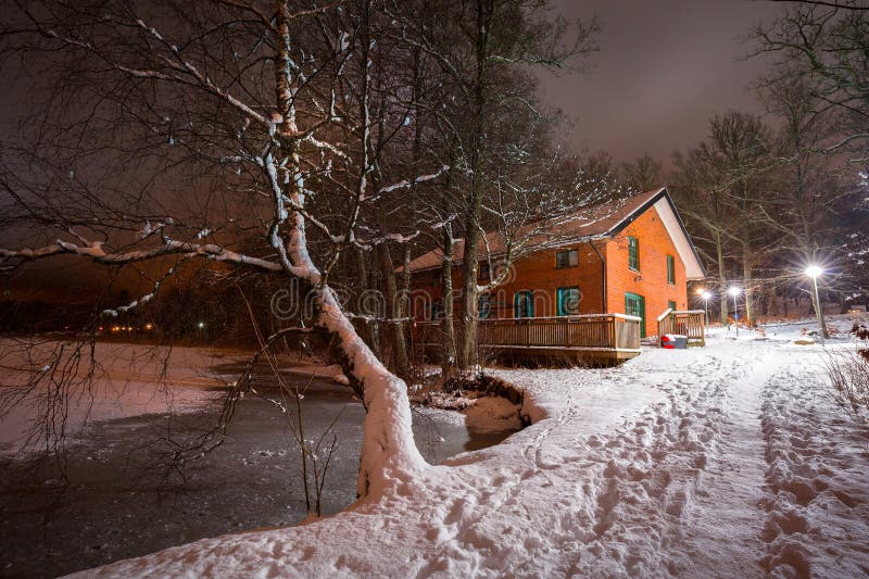 Litet stugahus nära sjön på den snöig natten royaltyfria bilder Litet stugahus nära sjön på den snöig natten royaltyfria bilder