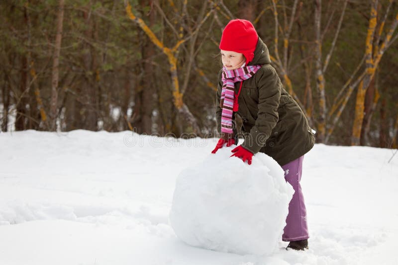 Litle girl rolling big snowball