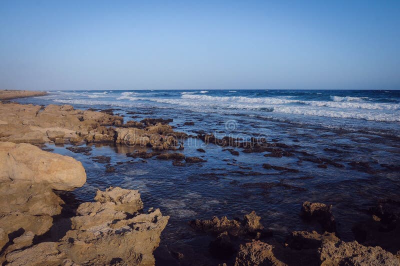 Litoral rochoso abandonado bonito da paisagem, ondas azuis. Litoral rochoso abandonado bonito da paisagem, fundo azul das ondas