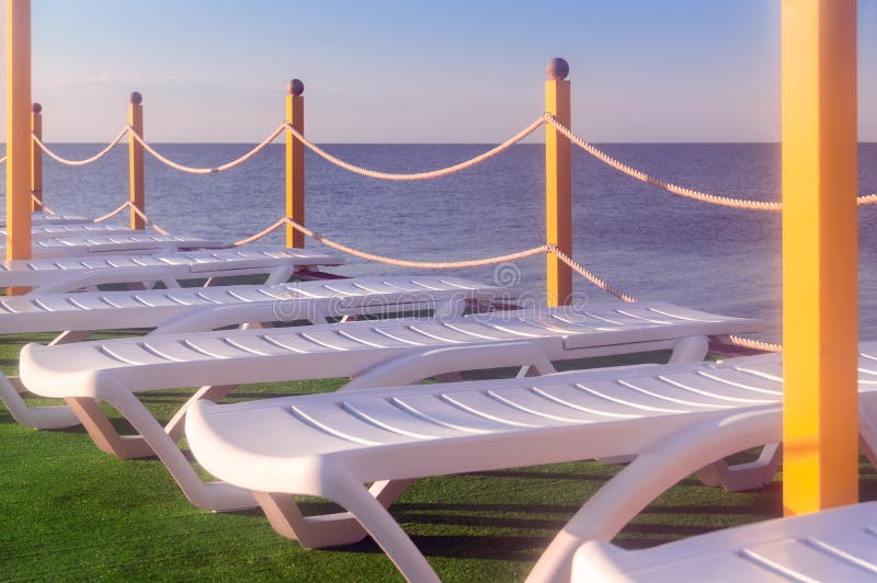 Lits pliants sur l'herbe par la mer photo stock Lits pliants sur l'herbe par la mer photo stock