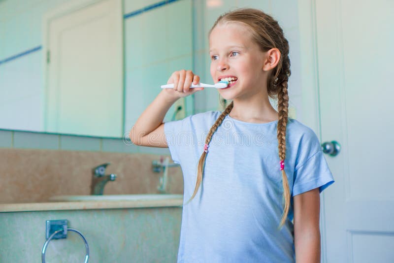 Little adorable girl brushes teeth in the bathroom. Perfect snow-white smile of little girl