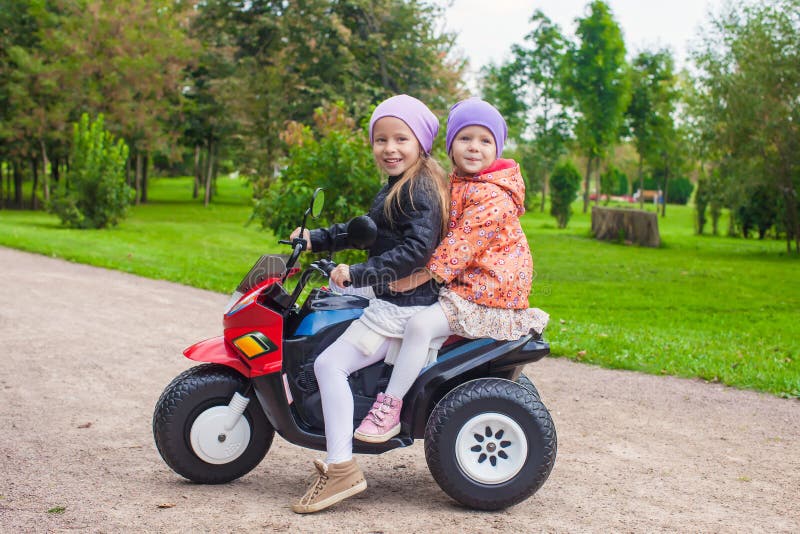 Little adorable sisters sitting on toy motorcycle