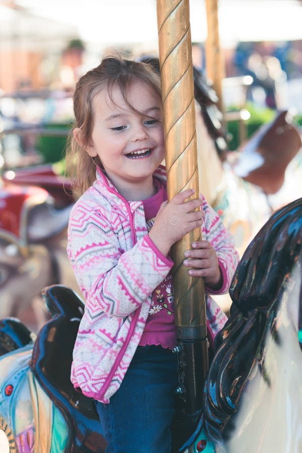 Little Adorable Smiling Girl Riding a Horse on Roundabout Carousel at ...