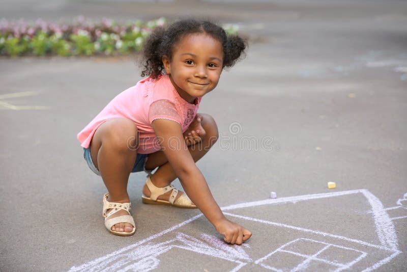 Little African-American child drawing house with chalk stock photo Little African-American child drawing house with chalk stock photo