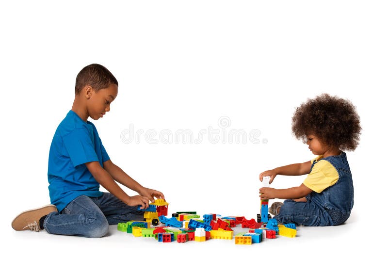 Two little cute african american children playing on the floor with lots of colorful plastic blocks in studio, isolated on white background. Two little cute african american children playing on the floor with lots of colorful plastic blocks in studio, isolated on white background