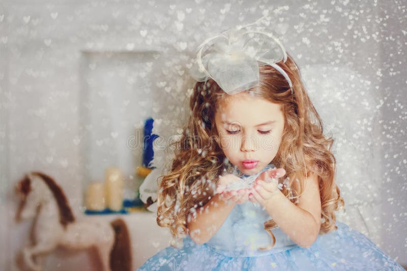 Little angel in light blue dress blowing snow