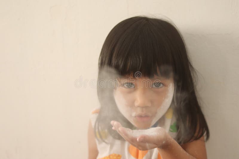 Little Asian baby girl playing with facial powder, blowing white powder on her face stock images