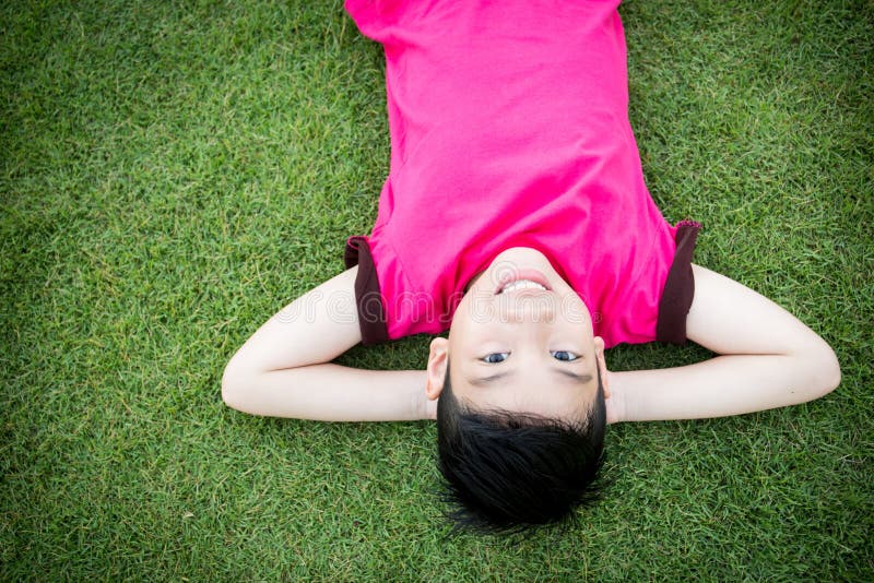 Little Asian child laying down on the grass royalty free stock images Little Asian child laying down on the grass royalty free stock images