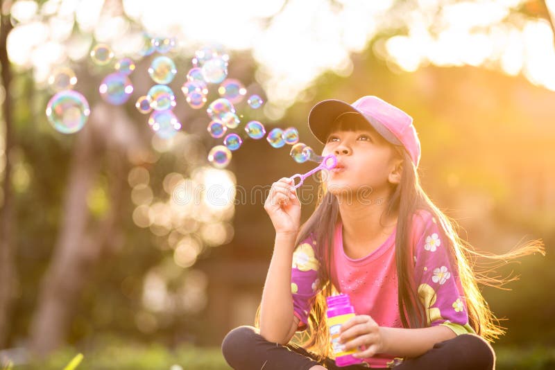 Little asian girl blowing soap bubbles