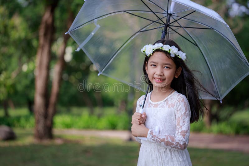 Little Asian girl holding clear umbrella and smiling with happiness select focus shallow depth of field royalty free stock photo Little Asian girl holding clear umbrella and smiling with happiness select focus shallow depth of field royalty free stock photo
