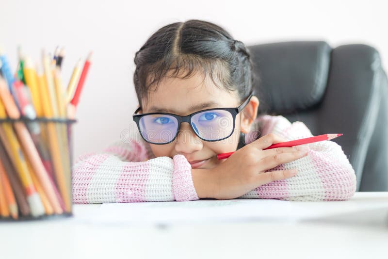 Little Asian girl holding the pencil to doing homework and smile with happiness for education concept select focus shallow depth