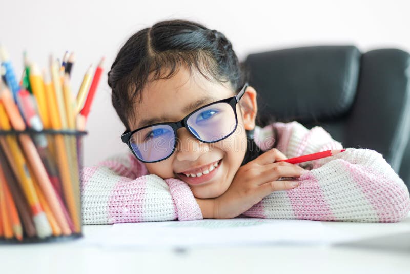 Little Asian girl holding the pencil to doing homework and smile with happiness for education concept select focus shallow depth