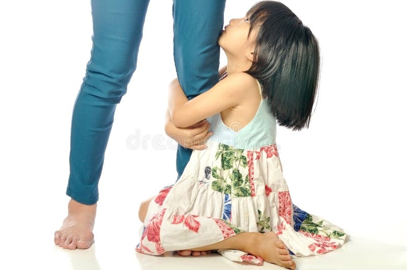 Little asian girl looking up and holding her mother leg