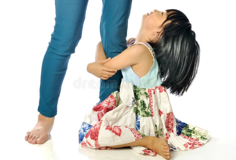 Little asian girl looking up and holding her mother leg