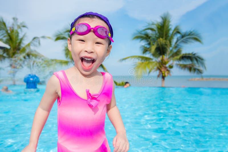 Little asian girl in pink swim suit smiling in outdoor swimming pool. Little asian girl in pink swim suit smiling in outdoor swimming pool