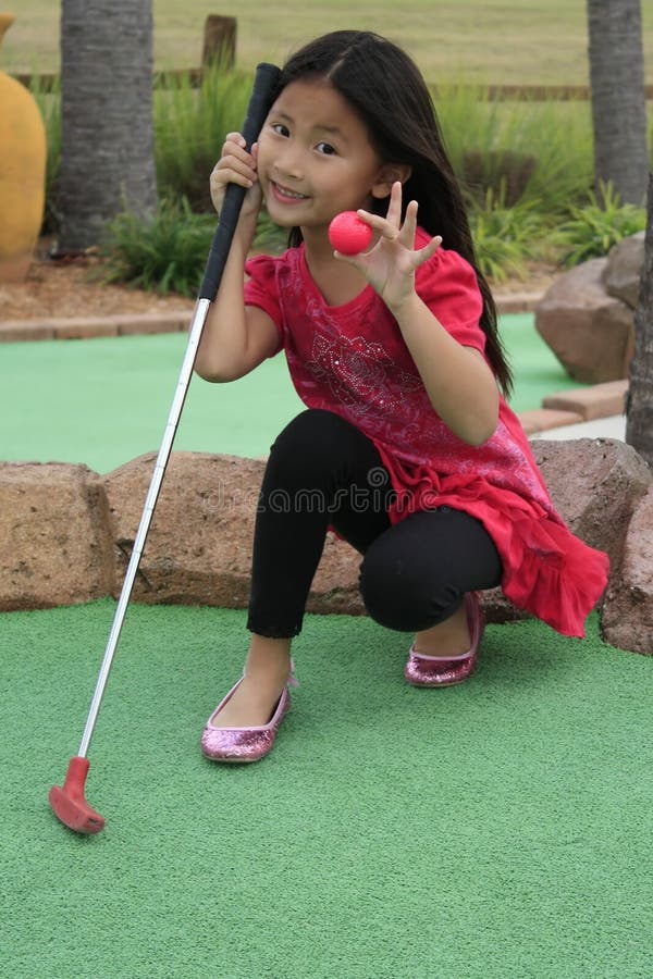 little girl playing mini golf