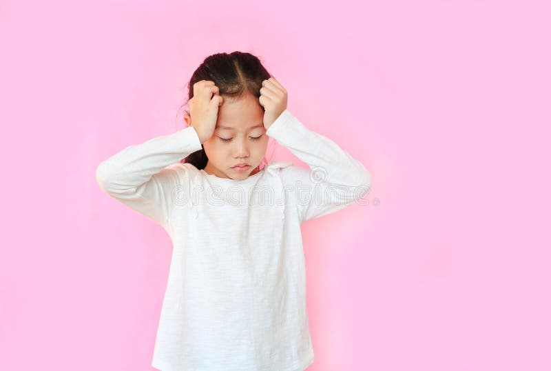 Little asian girl suffering from headache desperate and stressed because pain on pink background. Kid with hands on head royalty free stock photo Little asian girl suffering from headache desperate and stressed because pain on pink background. Kid with hands on head royalty free stock photo