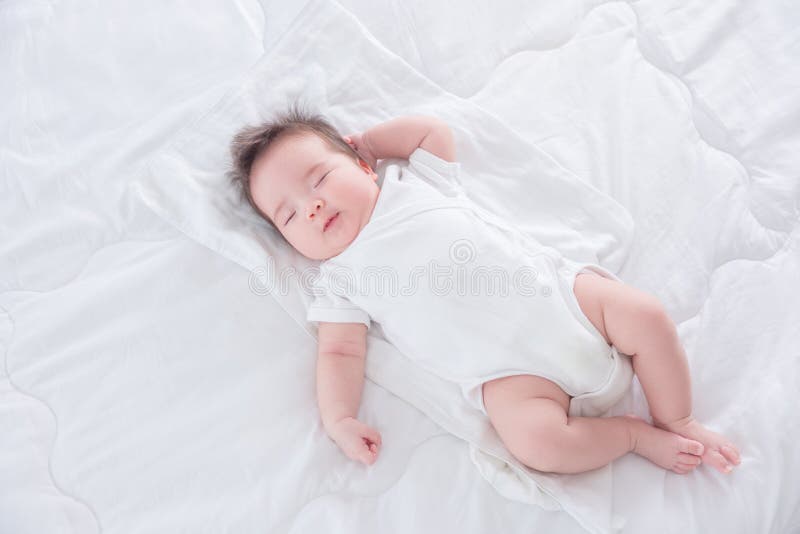 Infant sleeping on white bed in the morning