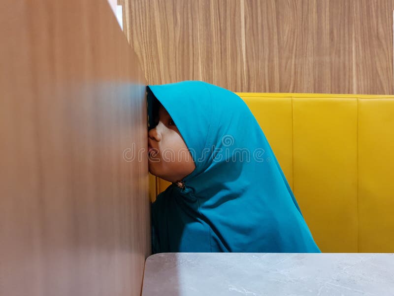 Little Asian muslim baby girl looked unhappy annoyed while sitting at cafe, tired kid feeling angry and lazy stock images