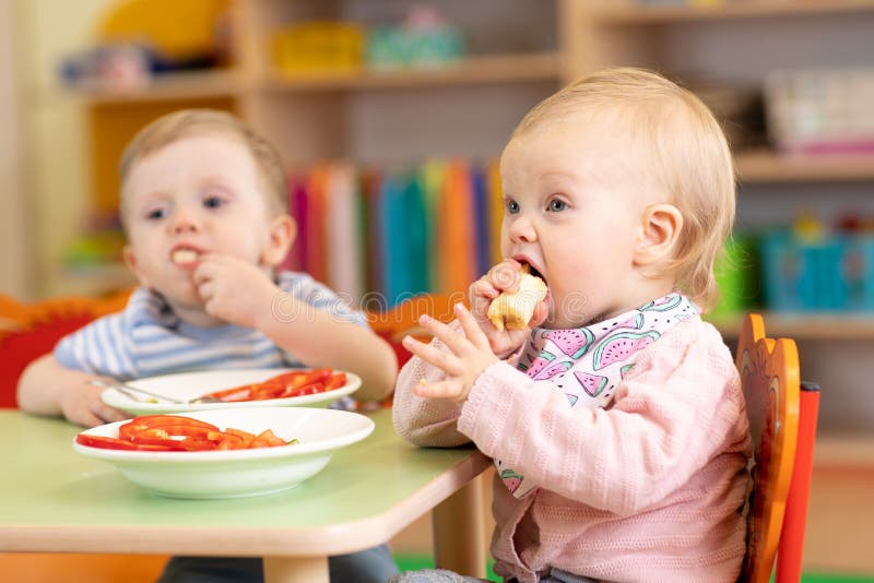 Little babies girl and boy eat fruits and vegetables