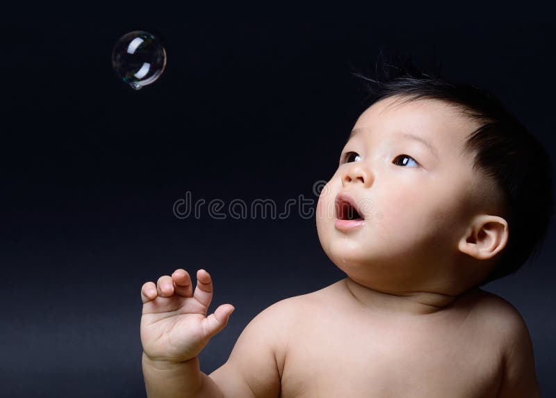 Little baby asian boy drooling and looking to soap bubble