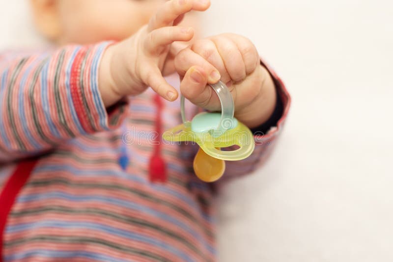 Little Baby Boy Holding a Pacifier Dummy in His Hand and Playing with