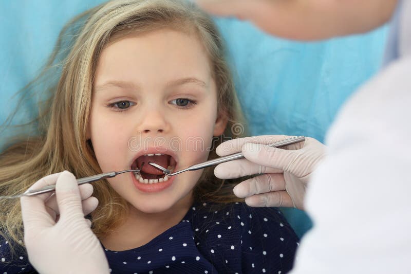 Little baby girl sitting at dental chair with open mouth and feeling fear during oral check up while doctor. Visiting royalty free stock images Little baby girl sitting at dental chair with open mouth and feeling fear during oral check up while doctor. Visiting royalty free stock images
