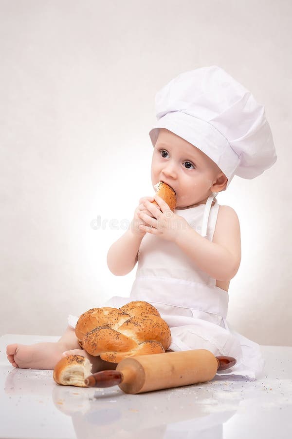 Little baker baby boy with loaf dressed in chef hat, laughing happily stock photo Little baker baby boy with loaf dressed in chef hat, laughing happily stock photo