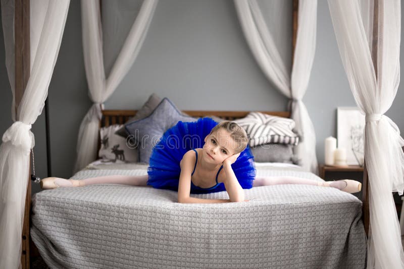 Little Ballerina Sitting on a Bed. Cute Little Girl Dreams of