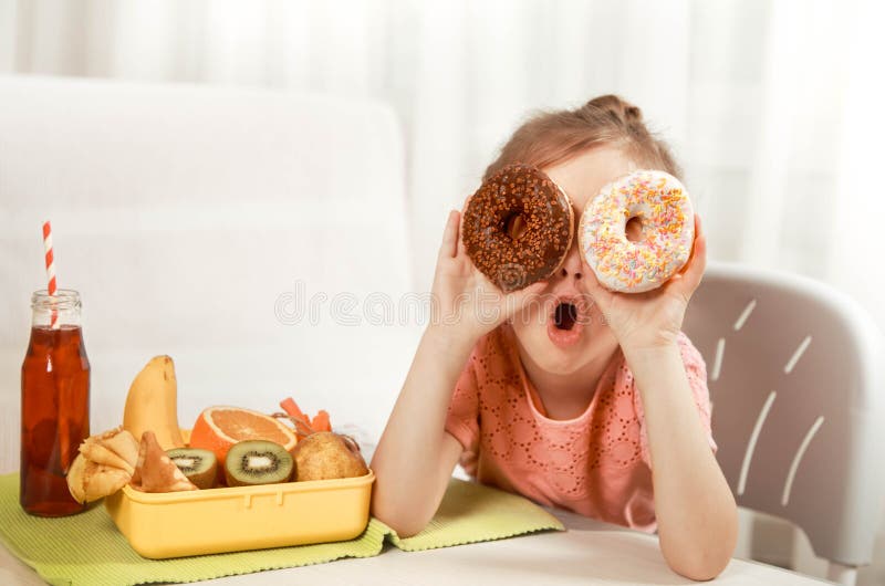 Little beautiful cheerful girl eating a donut