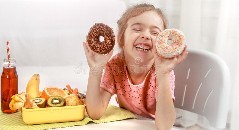 Little beautiful cheerful girl eating a donut