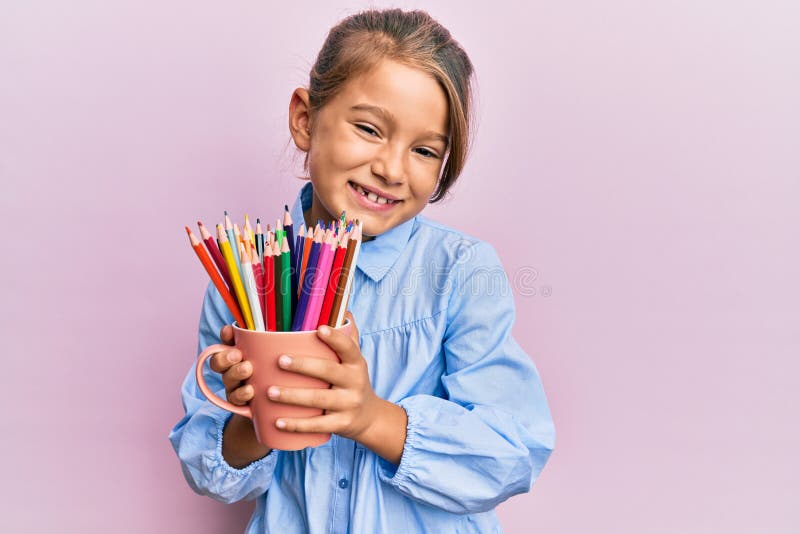 Little beautiful girl holding colored pencils smiling and laughing hard out loud because funny crazy joke