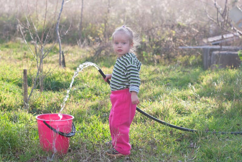 Little beautiful girl with hose and bucke