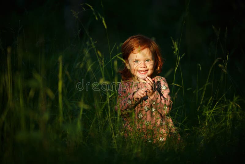 Little beautiful red-haired girl baby girl smiling, sitting in t