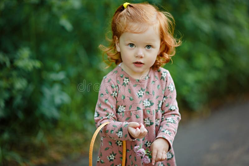 Little beautiful red-haired little girl looks seriously, summer